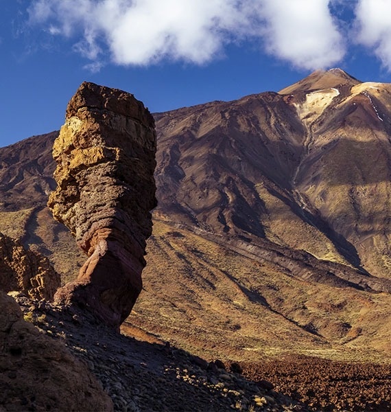 a large rock in the middle of a desert with mountains in the background