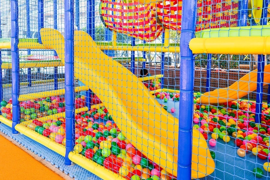 a child is playing in a ball pit with a slide .