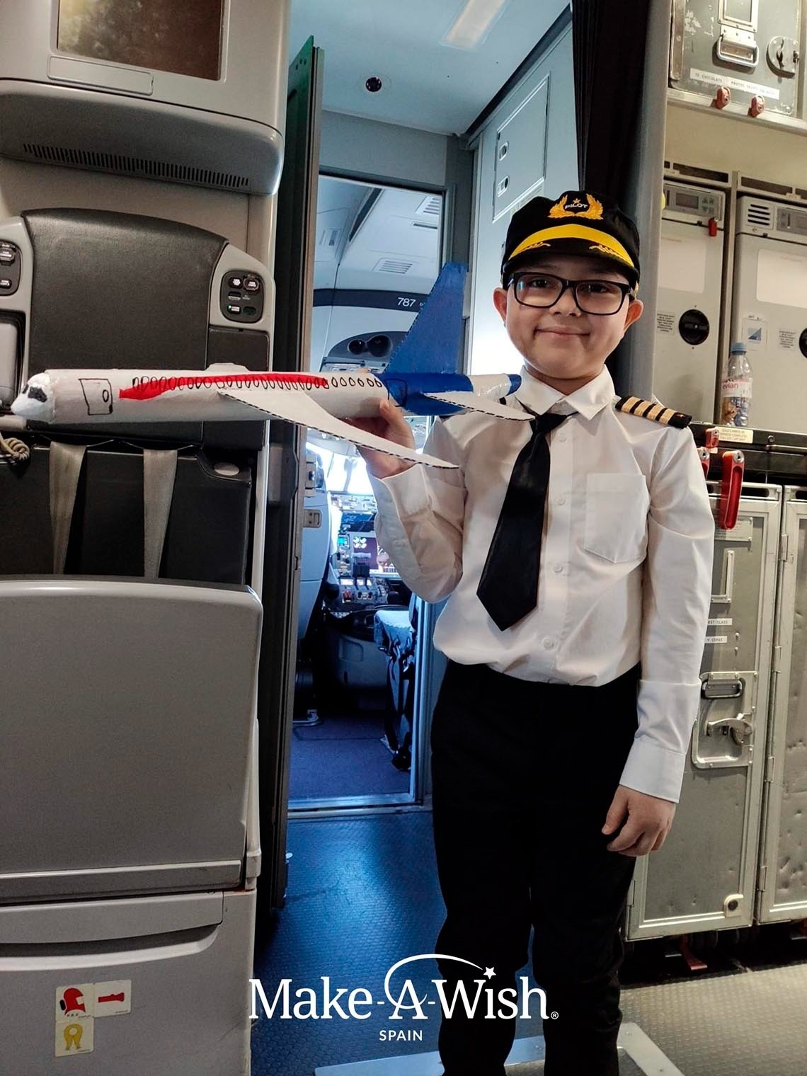 a young boy dressed as a pilot holds a model airplane in his hand