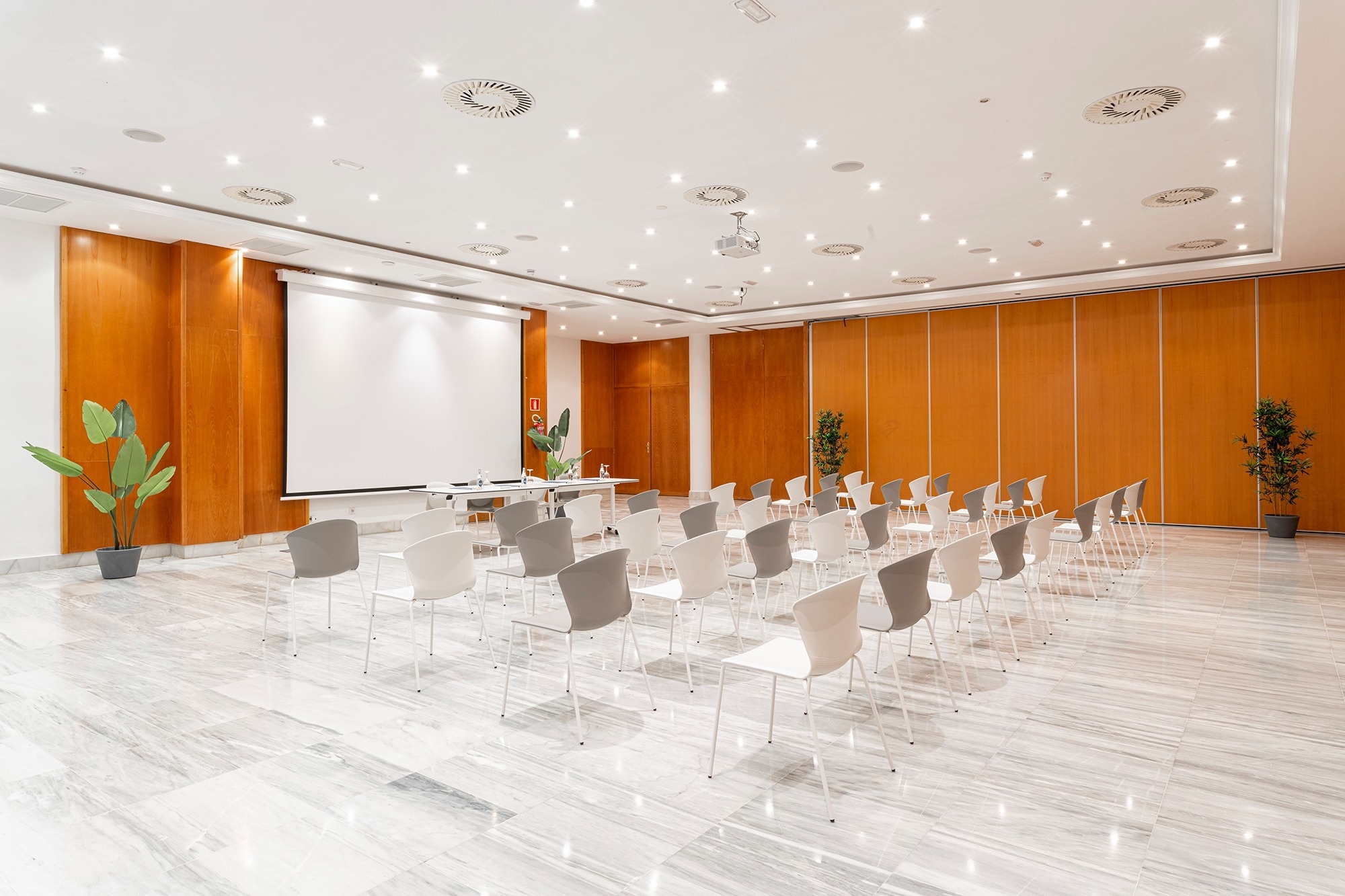 ein großer Raum mit vielen Stühlen und einem großen Bildschirm