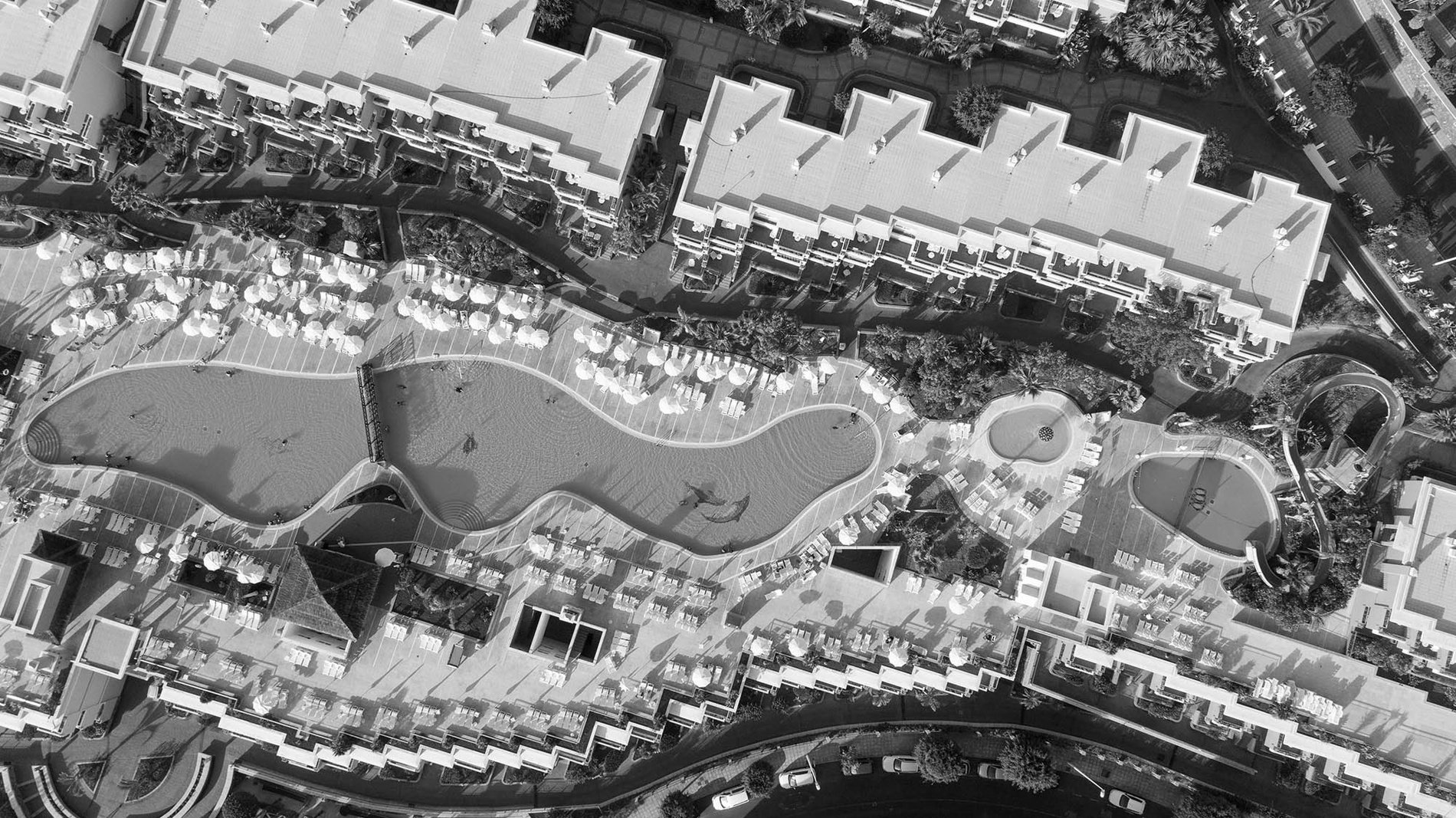 una vista aérea de un complejo de apartamentos con piscinas y sombrillas=s1900