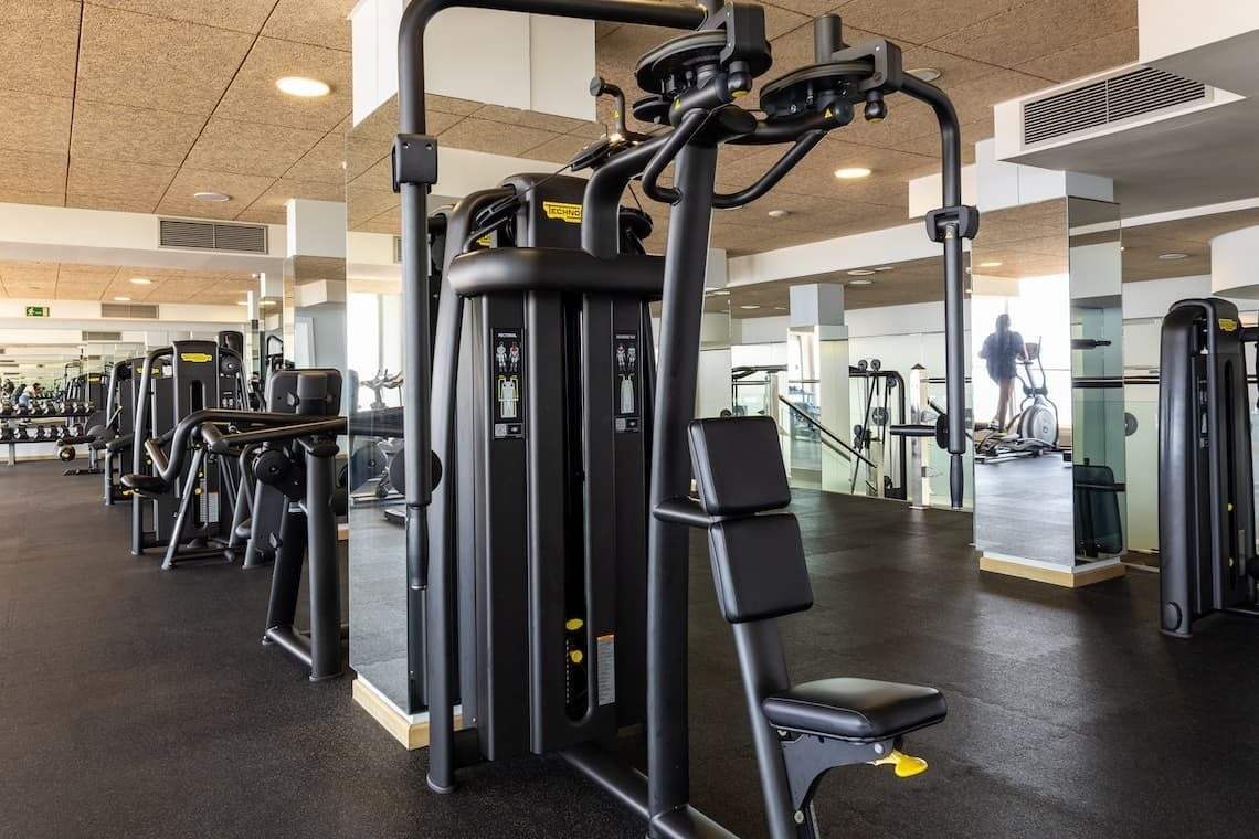 a gym filled with lots of exercise equipment and a man on an elliptical