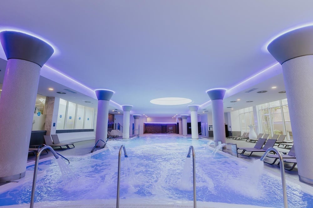 a large indoor swimming pool with blue lights on the ceiling