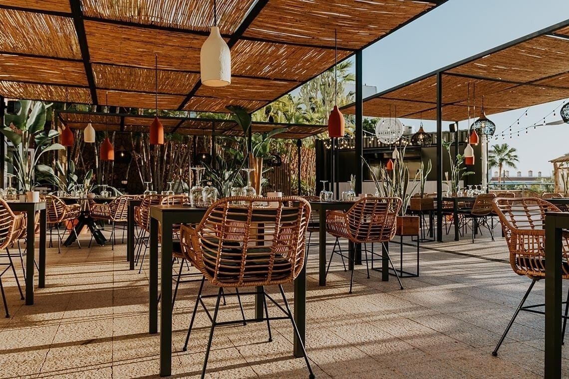 a restaurant with wicker chairs and tables under a canopy