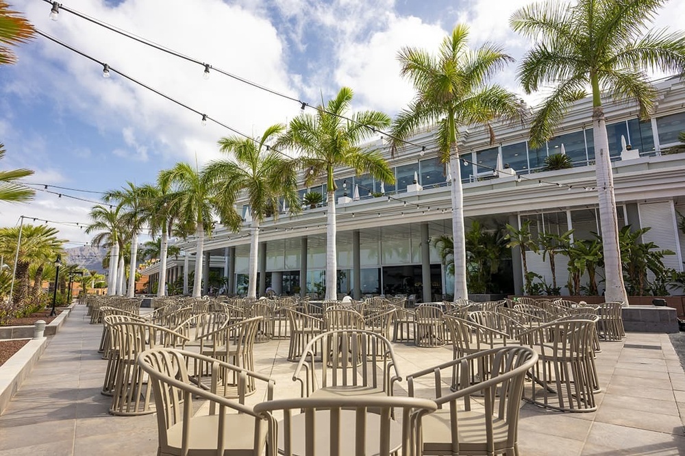 un grand bâtiment blanc avec des chaises et des tables à l' extérieur