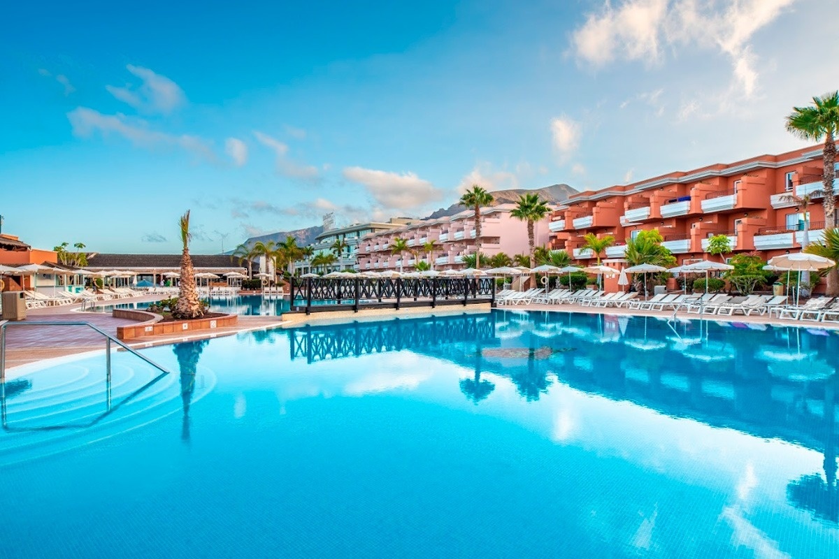 ein Hotel mit einem großen Pool und vielen Sonnenschirmen