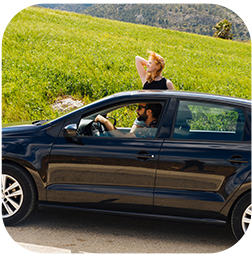 un homme conduit une voiture avec une femme debout sur le toit