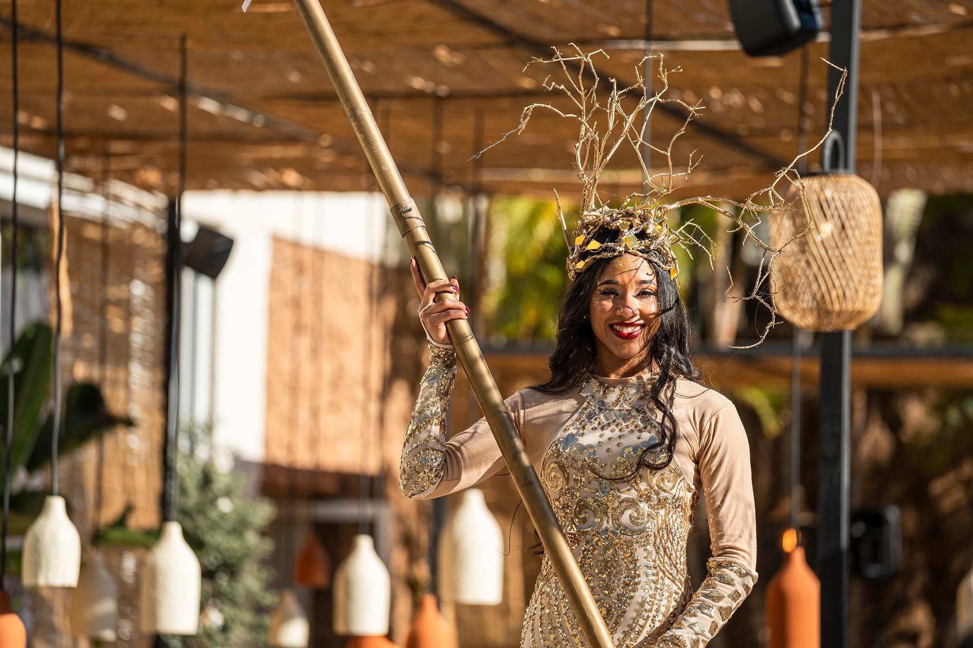 eine Frau in einem goldenen Kleid hält einen Bambusstab