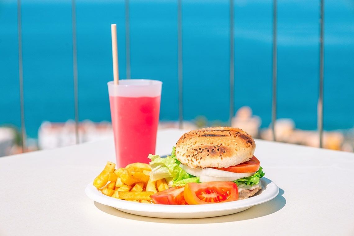 un plato de hamburguesa y papas fritas junto a un vaso de bebida rosa