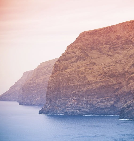 a large body of water with a cliff in the background