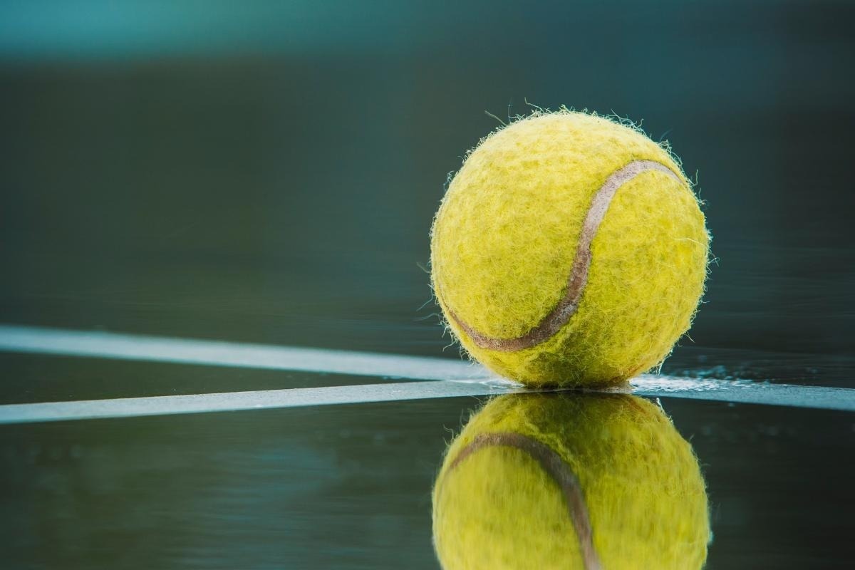 una pelota de tenis está sobre una superficie reflectante