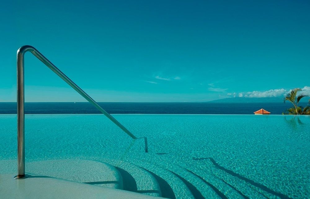 a woman in a white dress stands in front of a bush