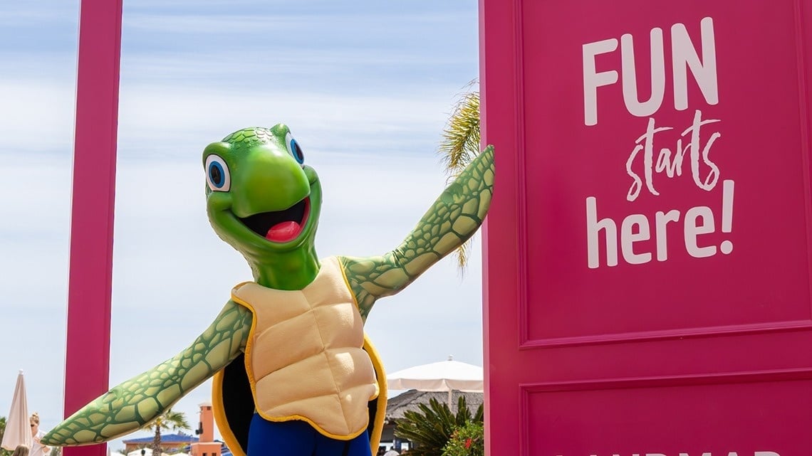 una tortuga está parada junto a una puerta rosa que dice 