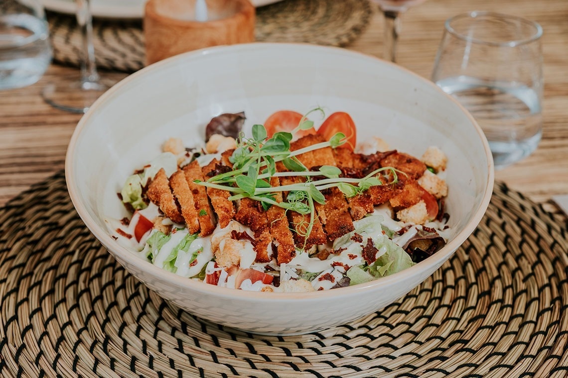 un bol de nourriture est assis sur une table à côté d' un verre d' eau