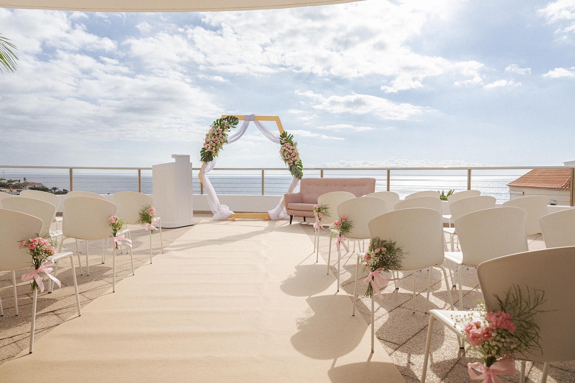 eine Reihe von weißen Stühlen auf einem Balkon mit Blick auf das Meer