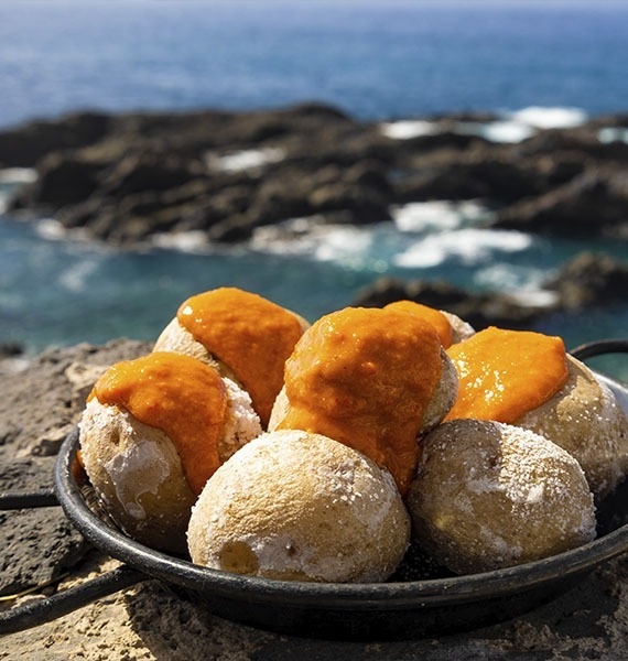 a person dipping a potato into a bowl of guacamole