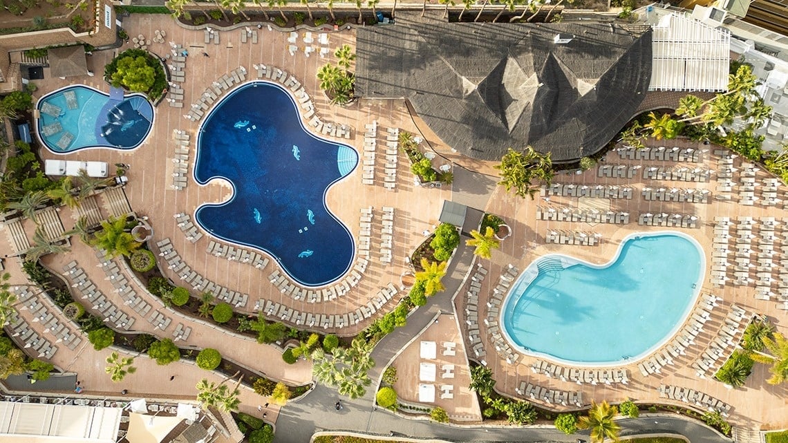 una vista aérea de una gran piscina rodeada de sillas y palmeras