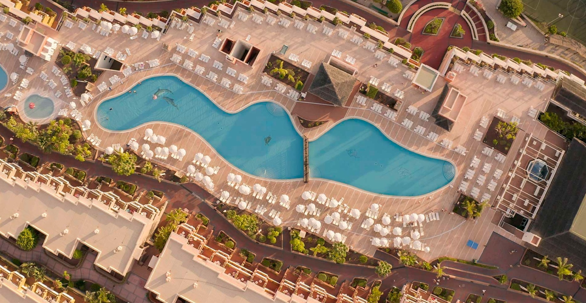 an aerial view of a large swimming pool surrounded by chairs and umbrellas
