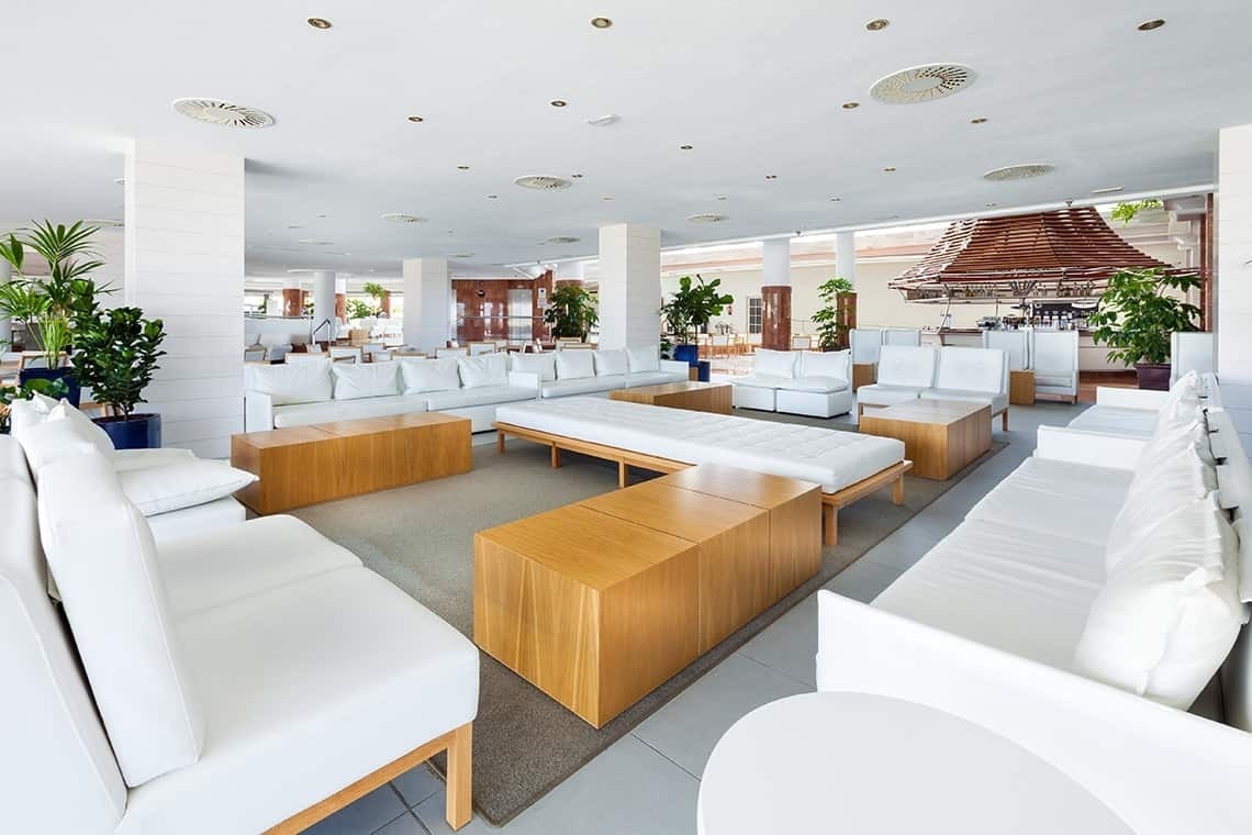 a living room with white furniture and a bar in the background