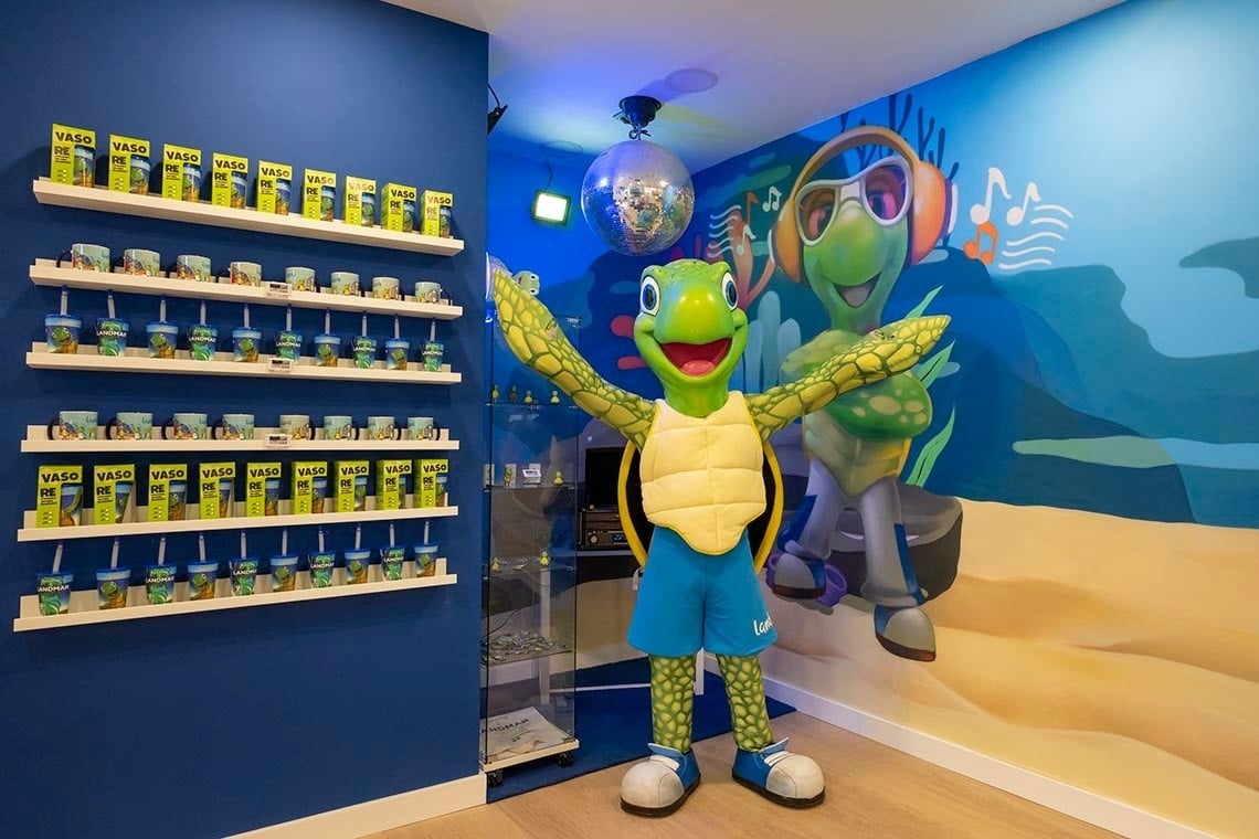 a turtle mascot stands in front of a wall of vaso cups