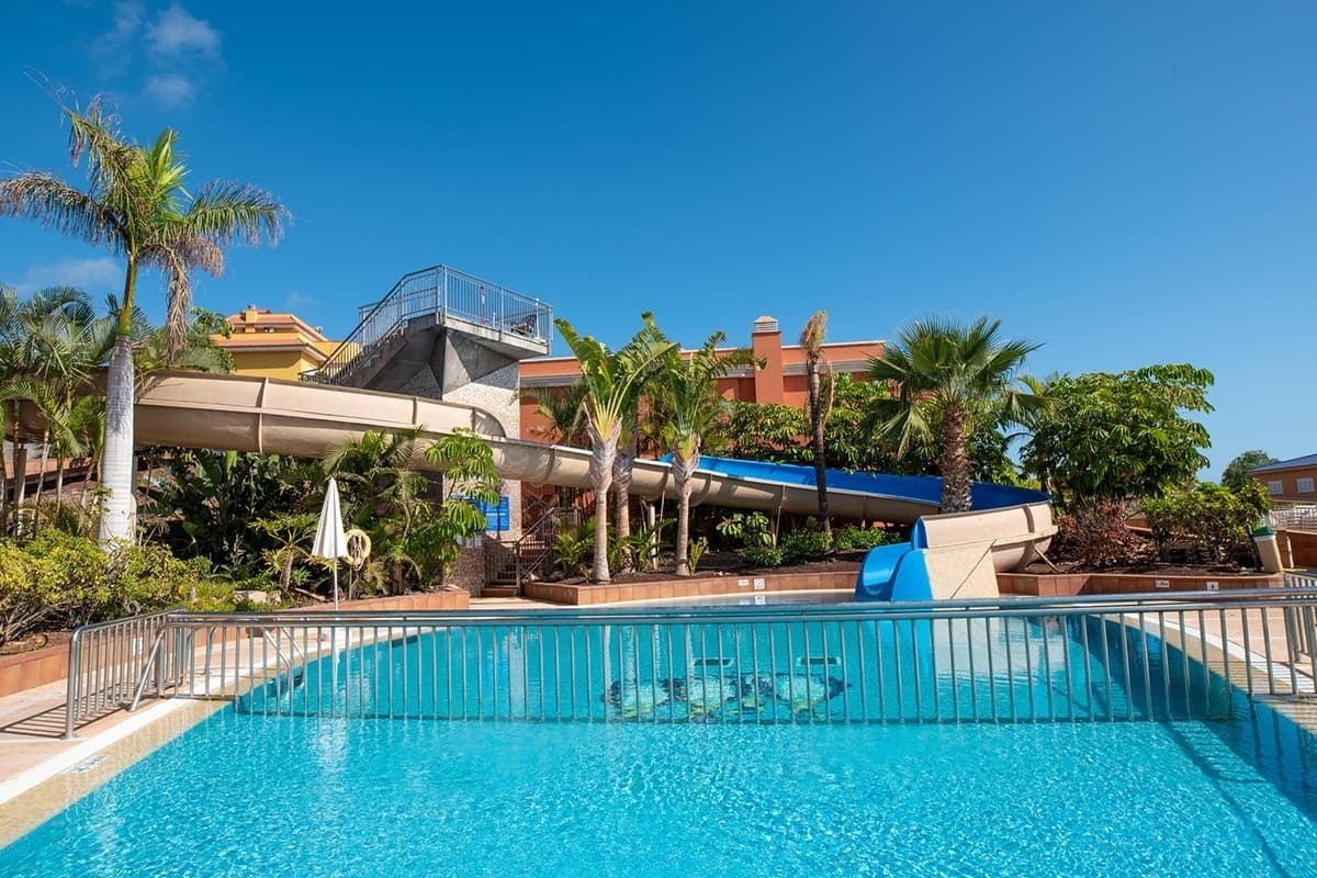 a large swimming pool with a water slide in the background