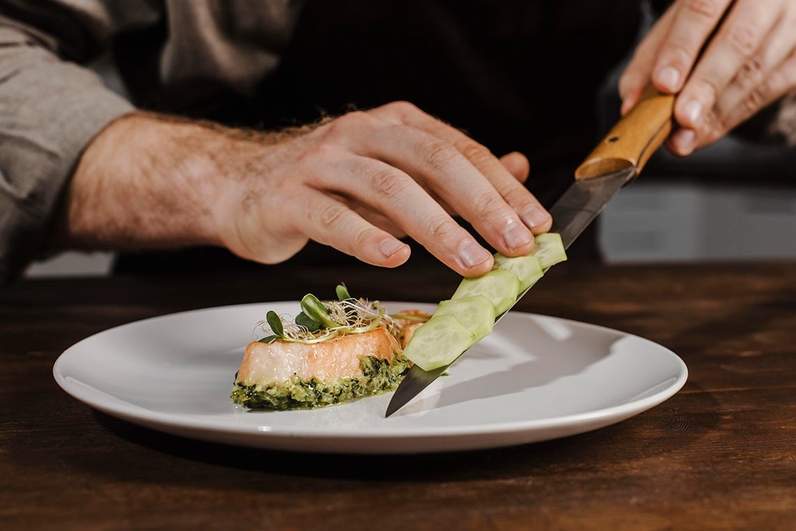 ein Mann schneidet einen Salat auf einem Teller mit einem Messer