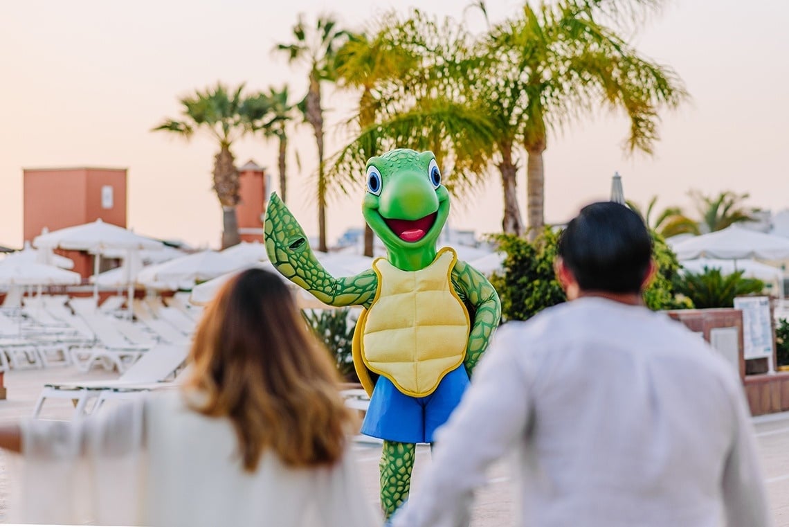 un hombre y una mujer se paran frente a una mascota de tortuga