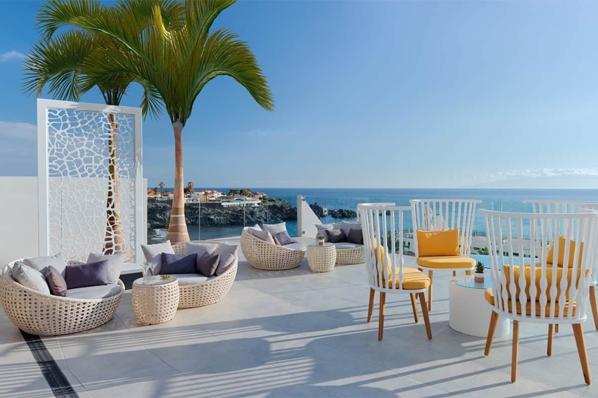 eine Terrasse mit Möbeln und Stühlen mit Blick auf den Ozean