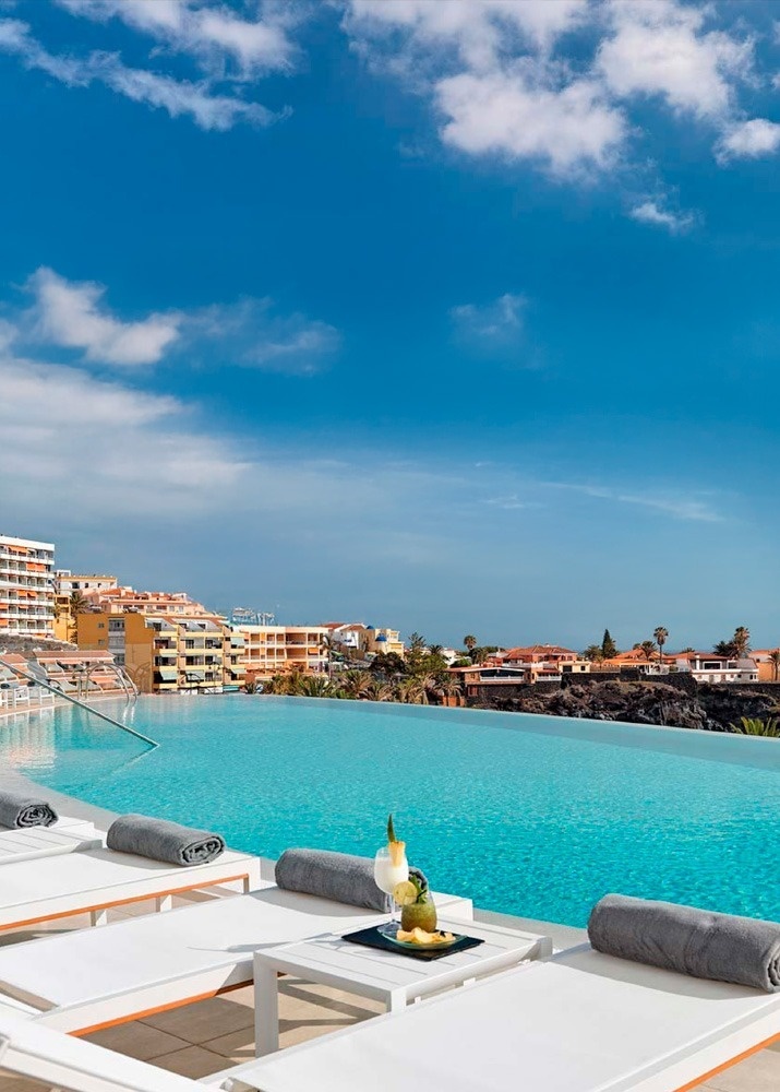 una piscina infinita con una bebida en la mesa