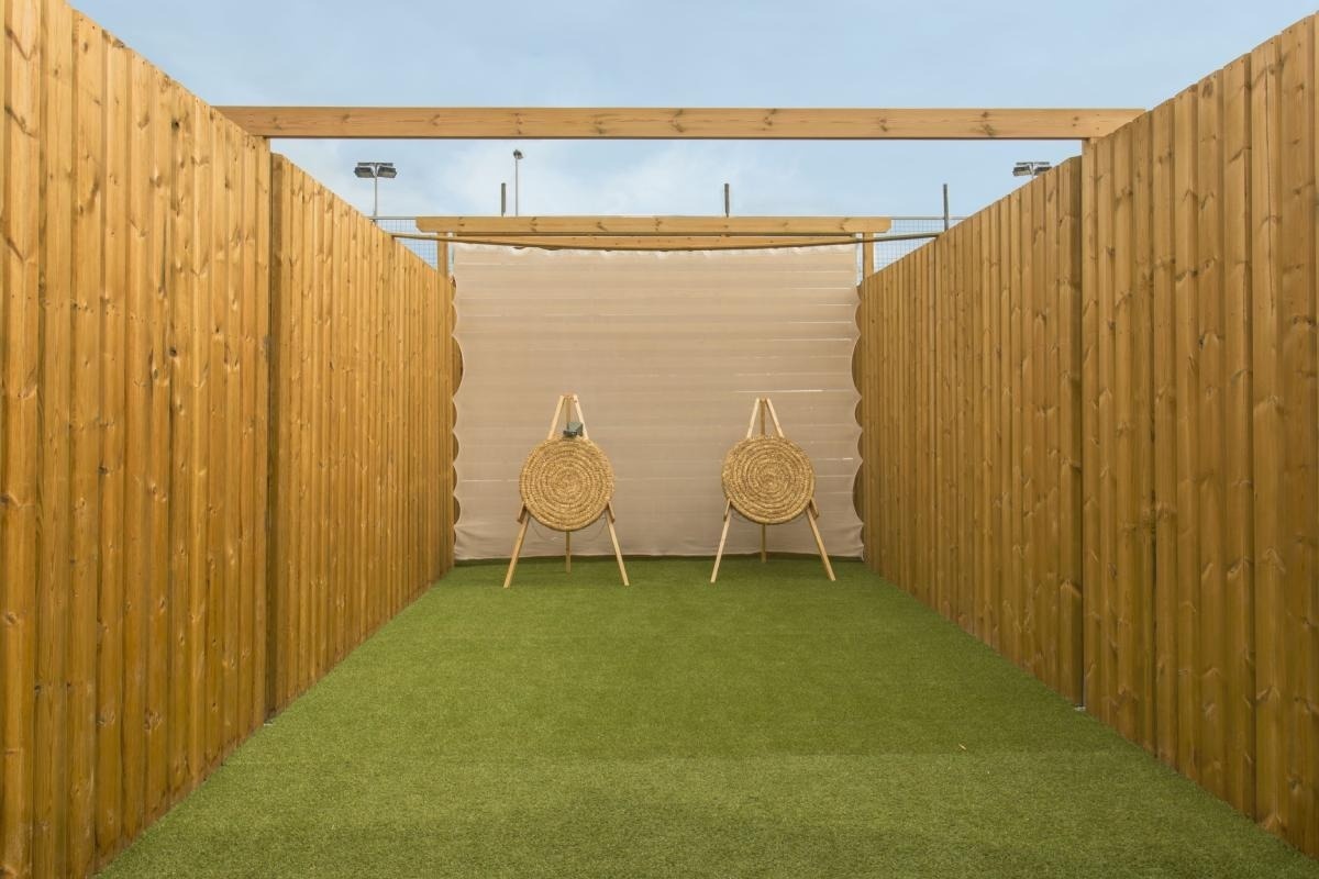 dos objetivos de tiro con arco están en un campo de hierba junto a una valla de madera