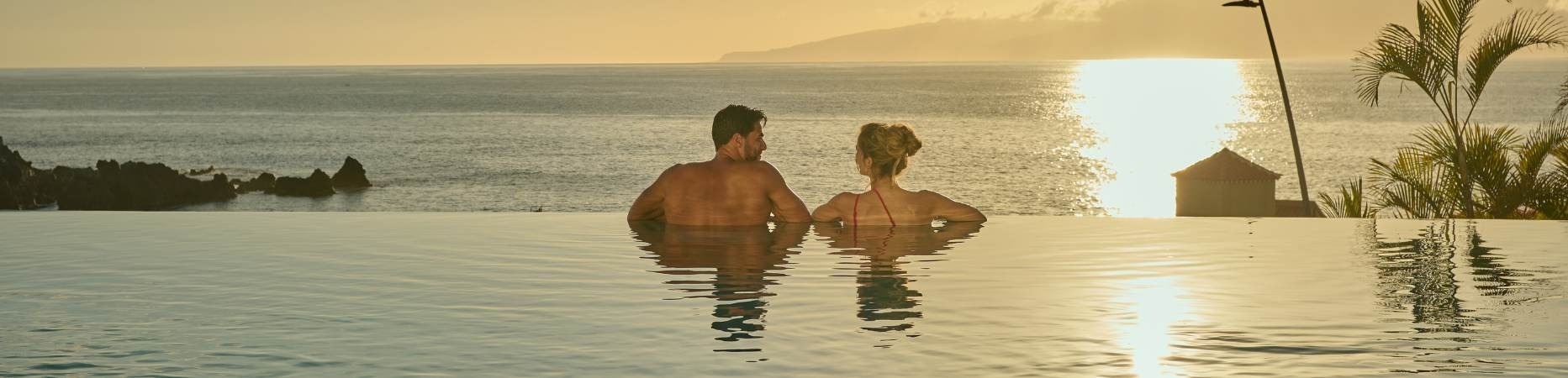 Paar, das den Pool mit Meerblick bei Sonnenuntergang genießt