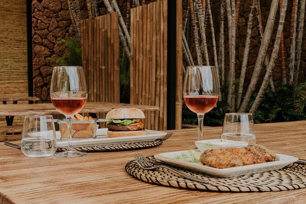 a table with a hamburger and wine glasses on it