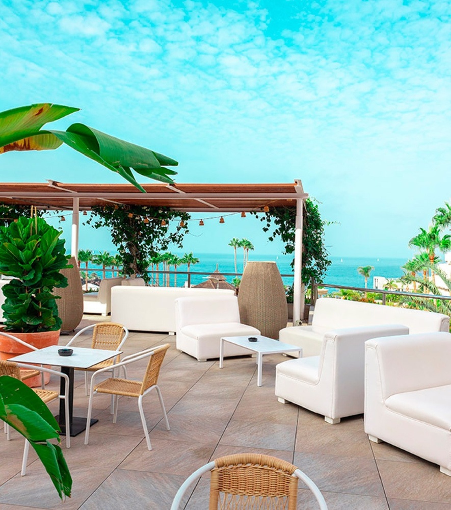 a woman in a striped dress sits in a canopy overlooking the ocean