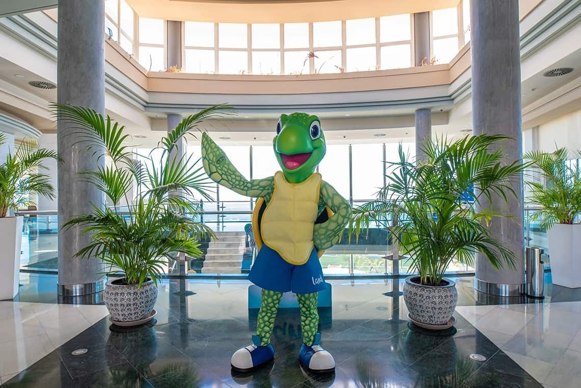 una mascota de tortuga con pantalones cortos azules y zapatos blancos