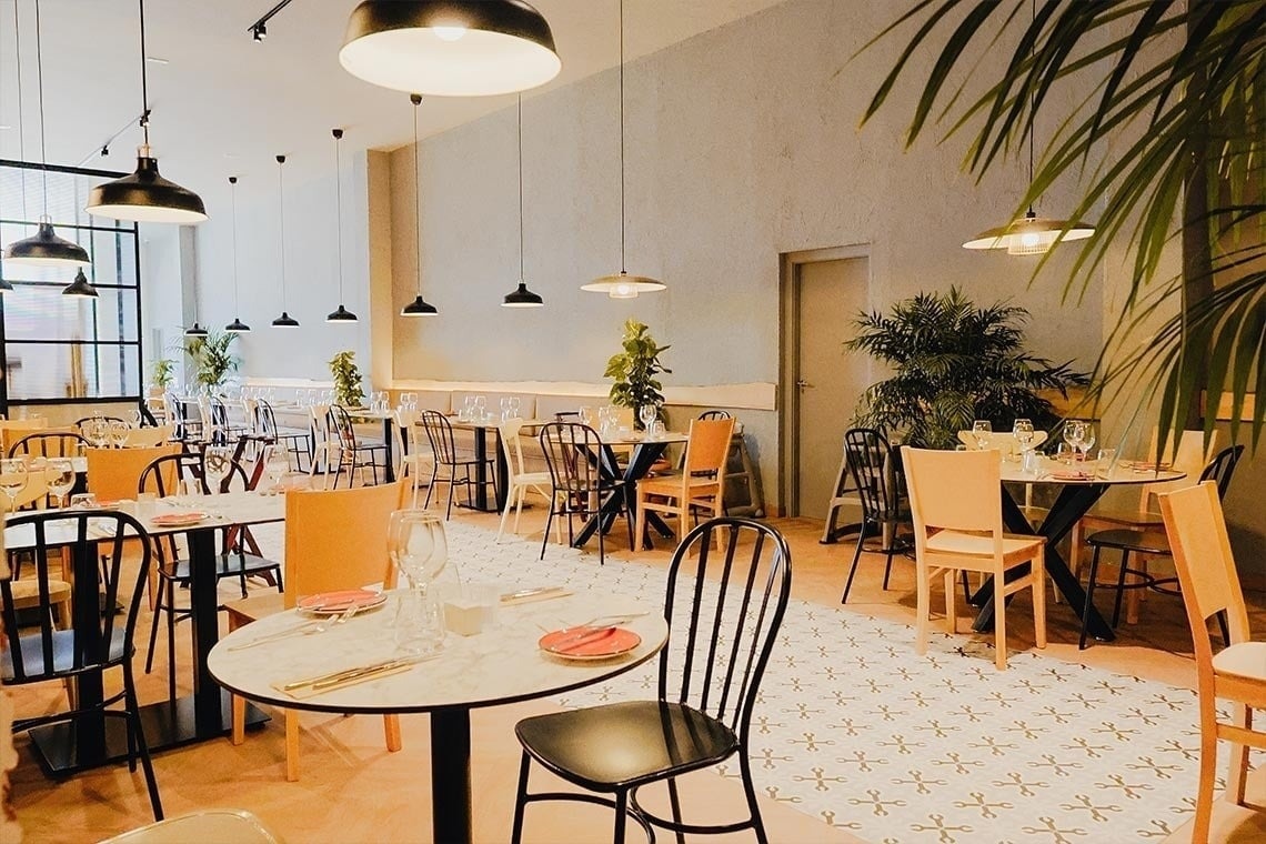 Elegante comedor de Landmar con mesas y sillas modernas, iluminación cálida.