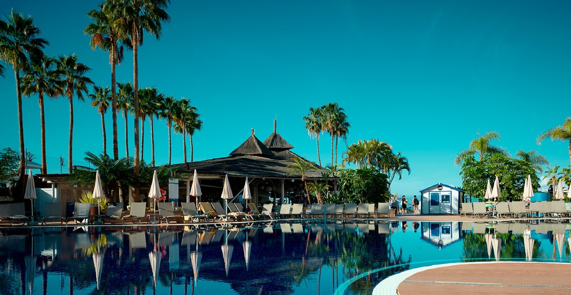 an aerial view of a large swimming pool surrounded by chairs and umbrellas
