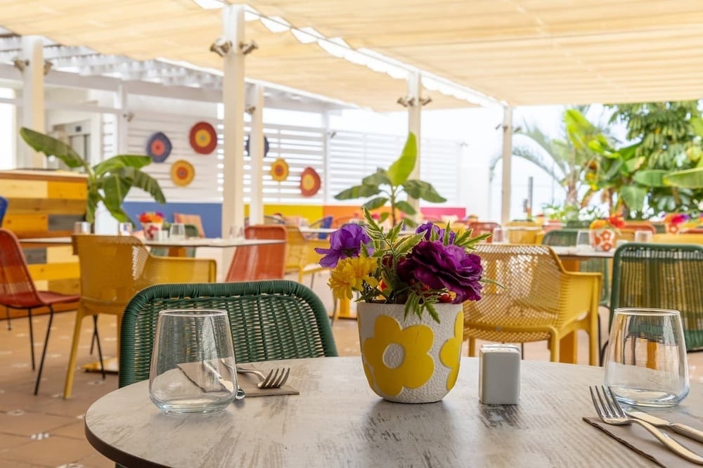 una mesa con vasos y cubiertos y un jarrón de flores