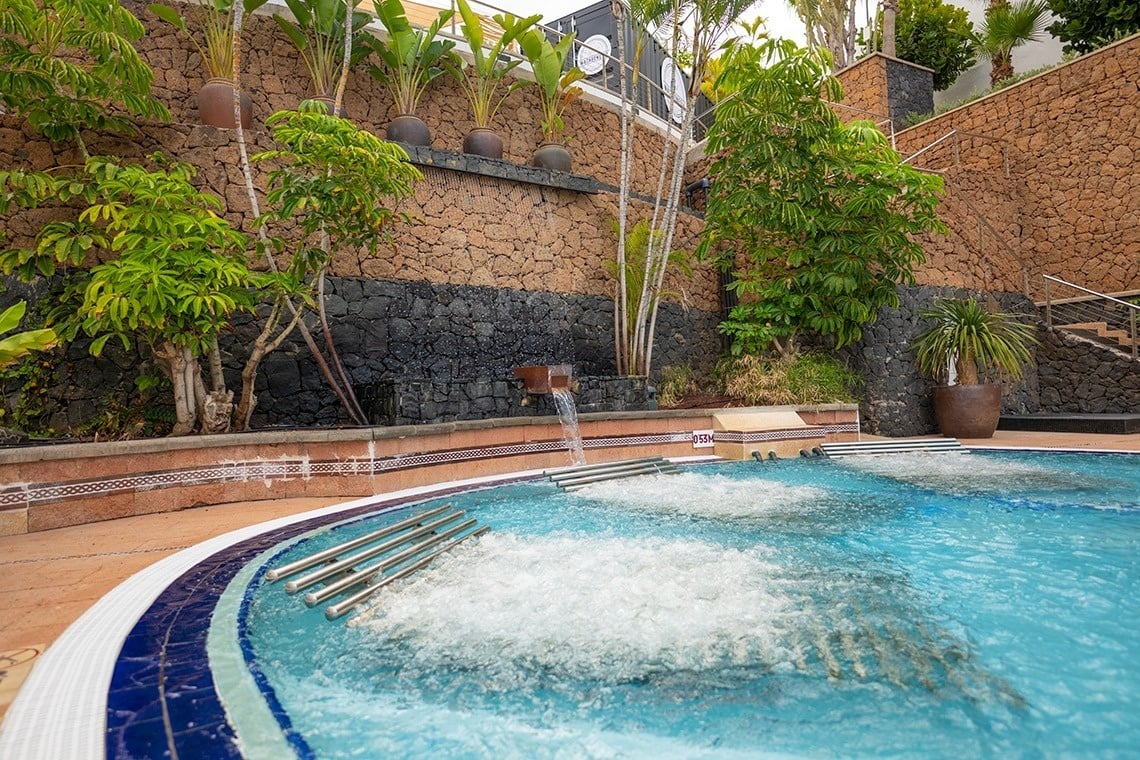una piscina con un jacuzzi y una cascada en el fondo