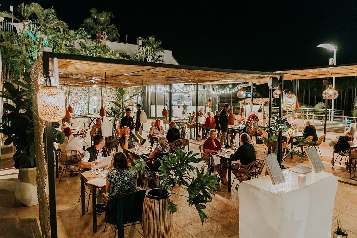 un groupe de personnes assises à des tables dans un restaurant la nuit