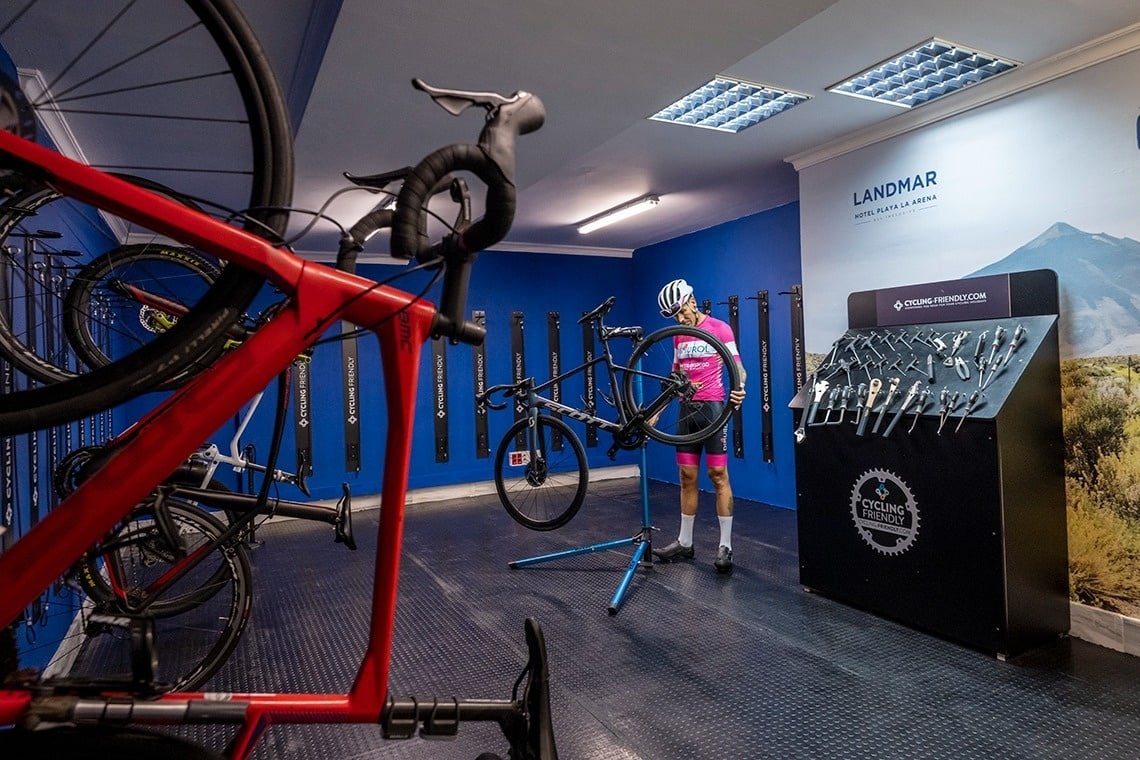 un hombre sostiene una bicicleta roja en un taller de reparación de bicicletas
