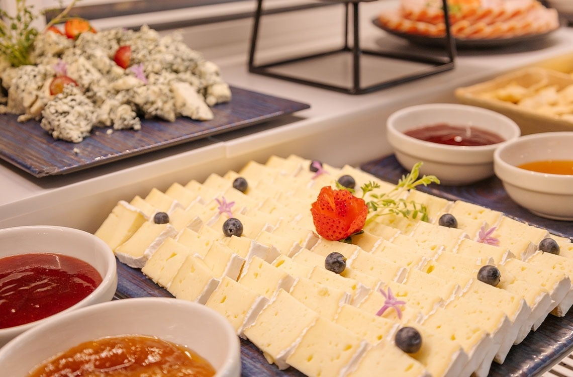 a tray of cheese with blueberries and a strawberry on top