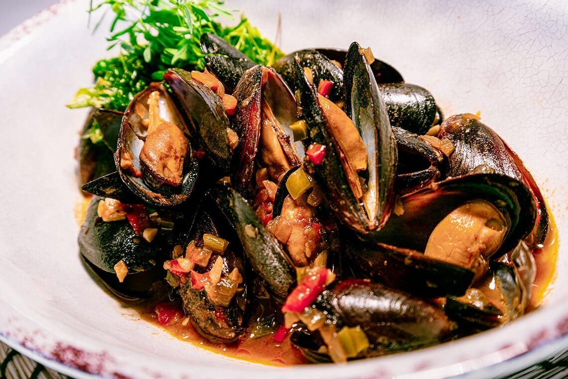 un plato blanco lleno de mejillones y verduras