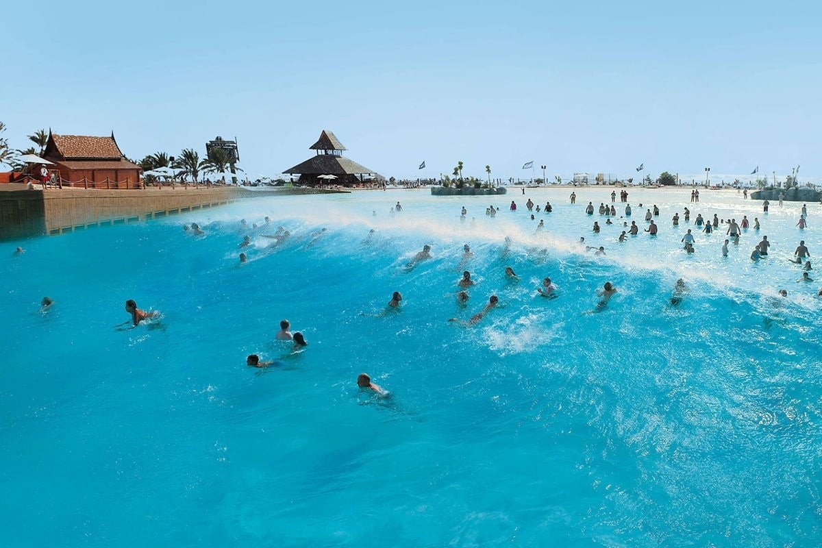 people are swimming in a large pool with a building in the background