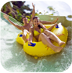 une femme tient un bébé dans une piscine sous une cascade d' eau