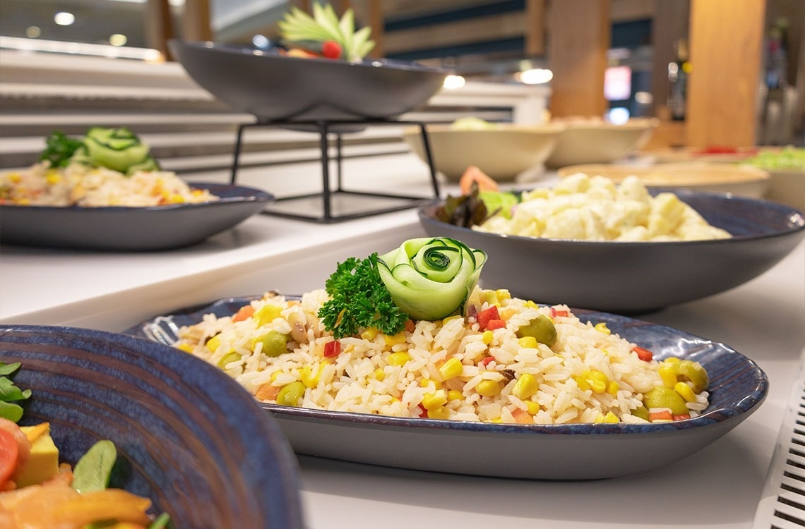 a plate of rice with vegetables and a cucumber on top