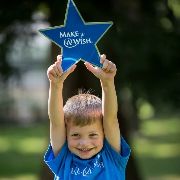 a young boy holds up a blue star that says make a wish