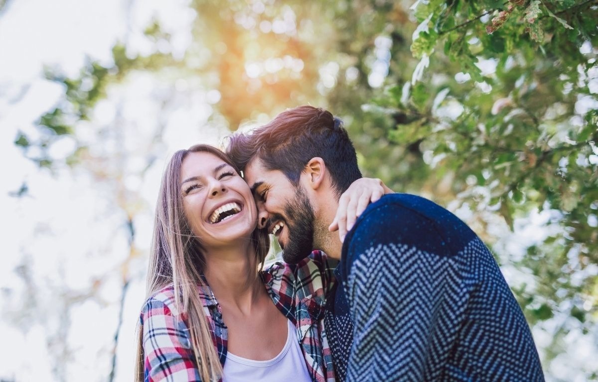 a man and a woman are laughing together in a park