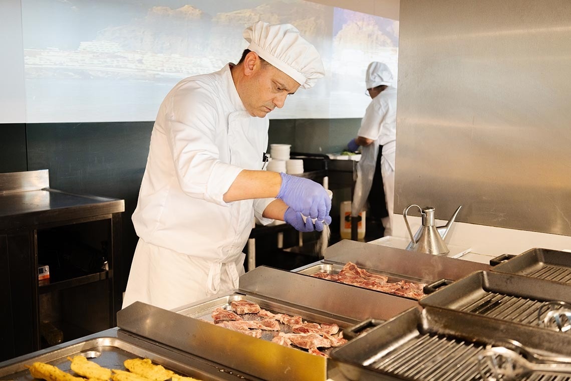 un chef prepara comida en una cocina con guantes azules