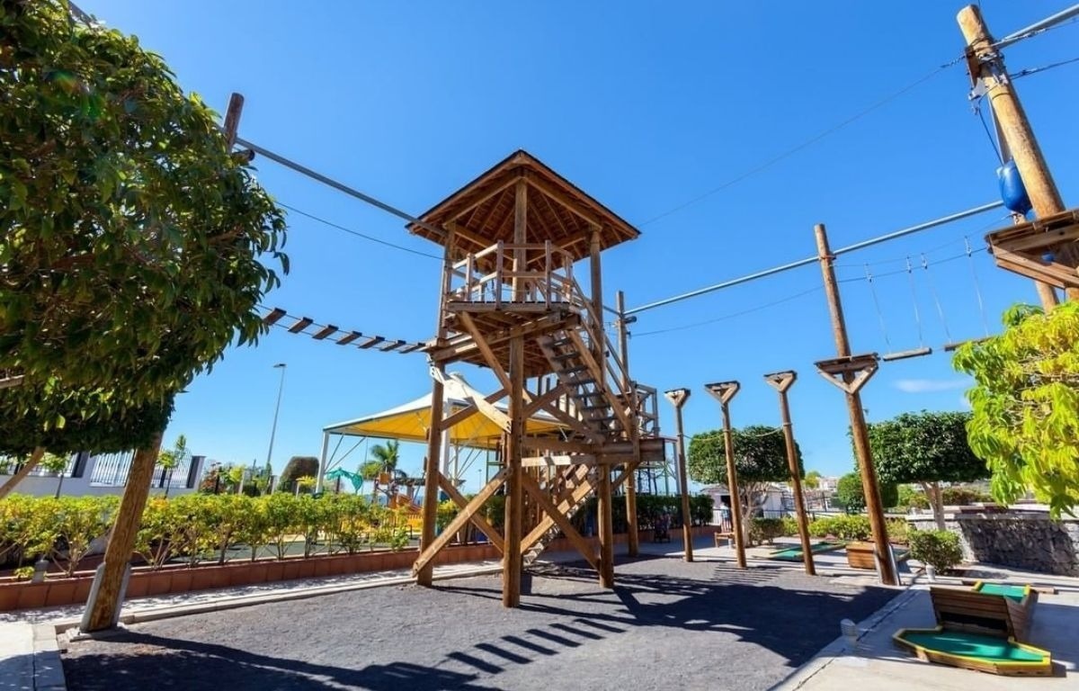 ein Spielplatz mit einem Holzturm und Seilbahnen