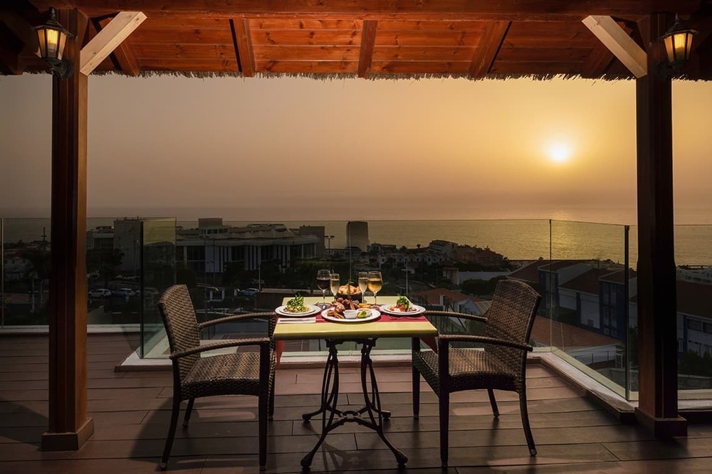 une table avec des assiettes et des verres sur une terrasse avec vue sur l' océan